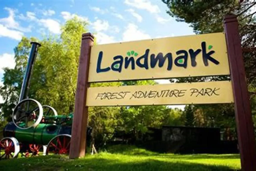 a sign for a park with a green car in the grass at The Snug at the Ski Lodge, Aviemore in Aviemore