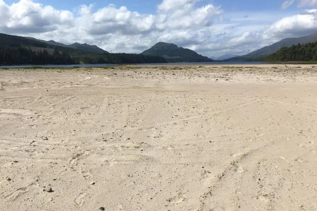 an empty beach with mountains in the background at The Snug at the Ski Lodge, Aviemore in Aviemore