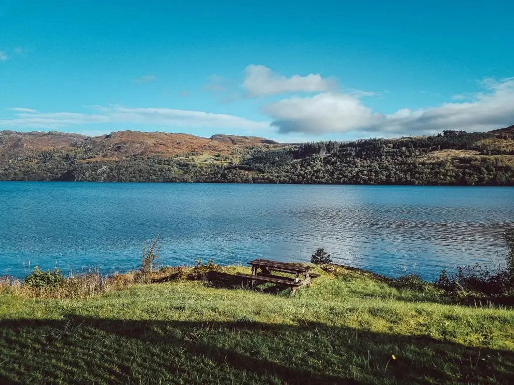 a bench sitting on the side of a lake at Cabins at Old Pier House in Fort Augustus