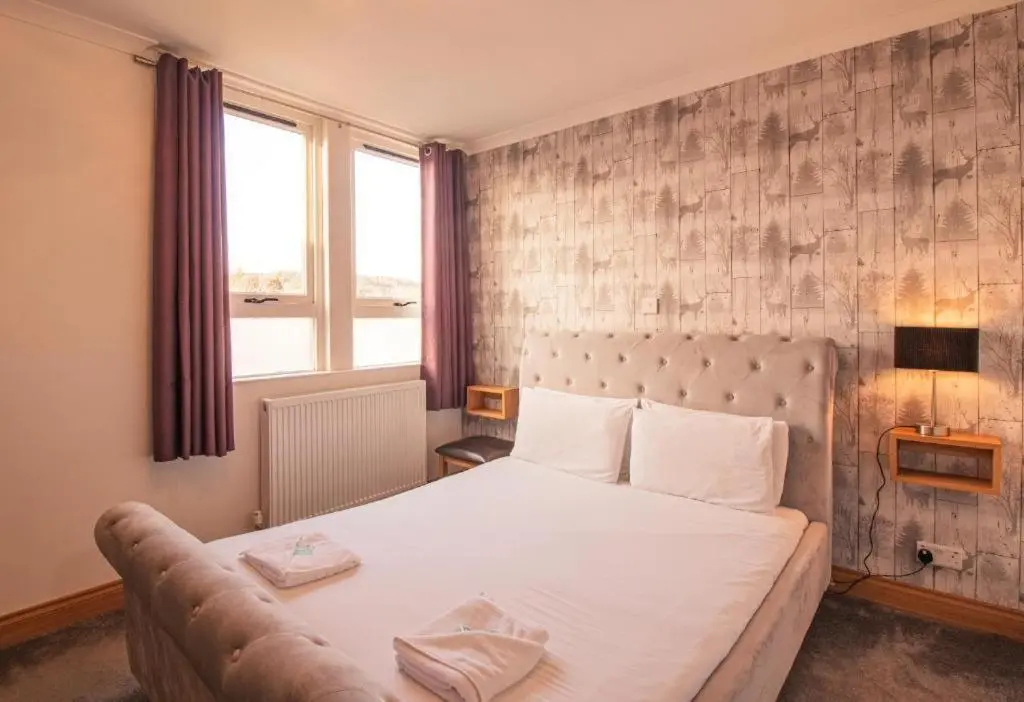 a bedroom with a large white bed with a couch at The Ben Mhor Hotel, Bar & Restaurant in Grantown on Spey