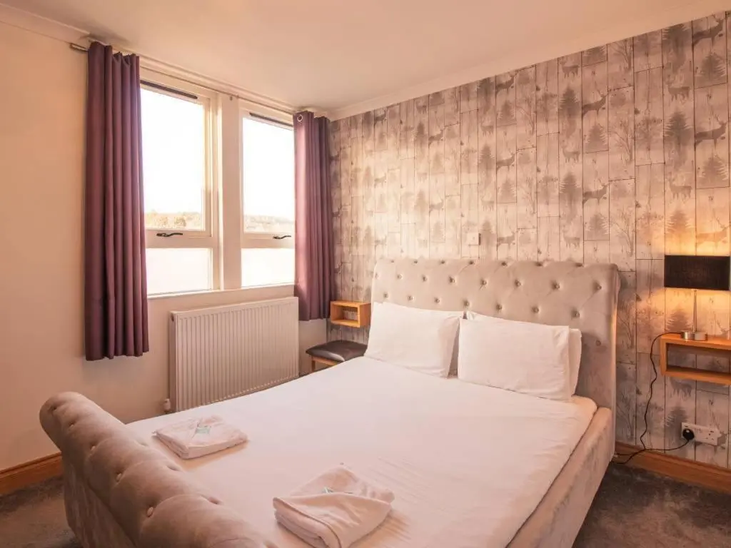 a bedroom with a large white bed with a couch at The Ben Mhor Hotel, Bar & Restaurant in Grantown on Spey