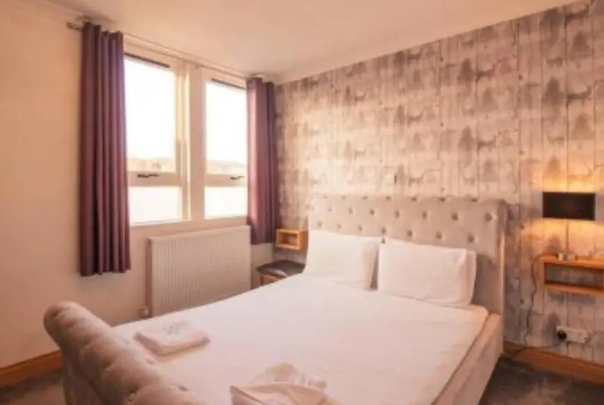 a bedroom with a large white bed and a window at The Ben Mhor Hotel, Bar & Restaurant in Grantown on Spey