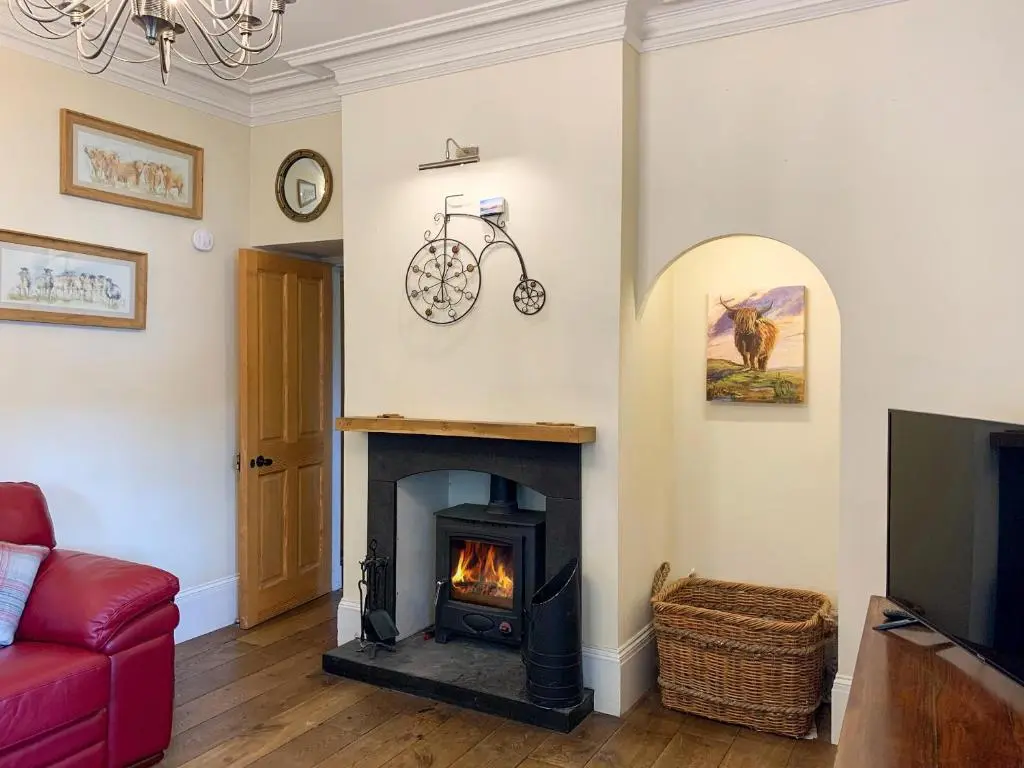 a living room with a fireplace and a red couch at Sluice Keeper's Cottage in Skelbo