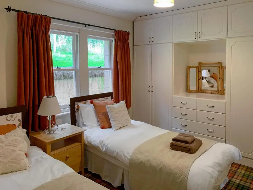 a bedroom with two beds and a window at Sluice Keeper's Cottage in Skelbo