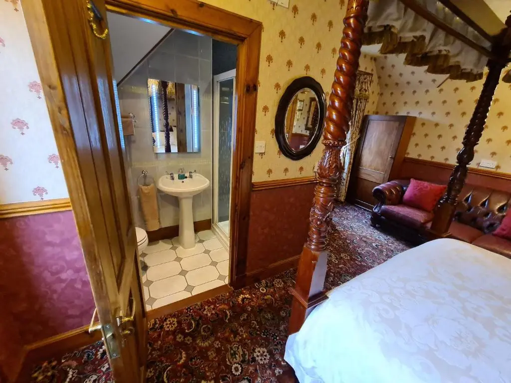 a bedroom with a bed and a bathroom with a sink at Bluebell House in Inverness