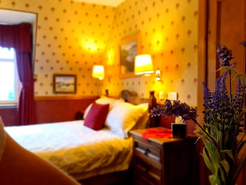 a bedroom with a bed and two lamps on the wall at Bluebell House in Inverness