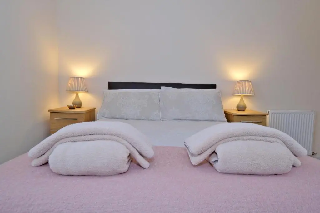 a bedroom with a large bed with two lamps at Caledonia Newhills Apartment in Aberdeen