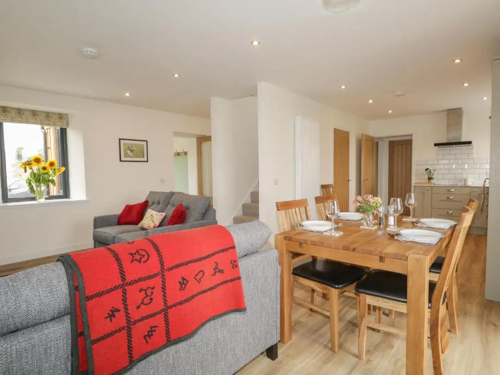 a living room and dining room with a table and a couch at Enzie Station Cottage in Buckie