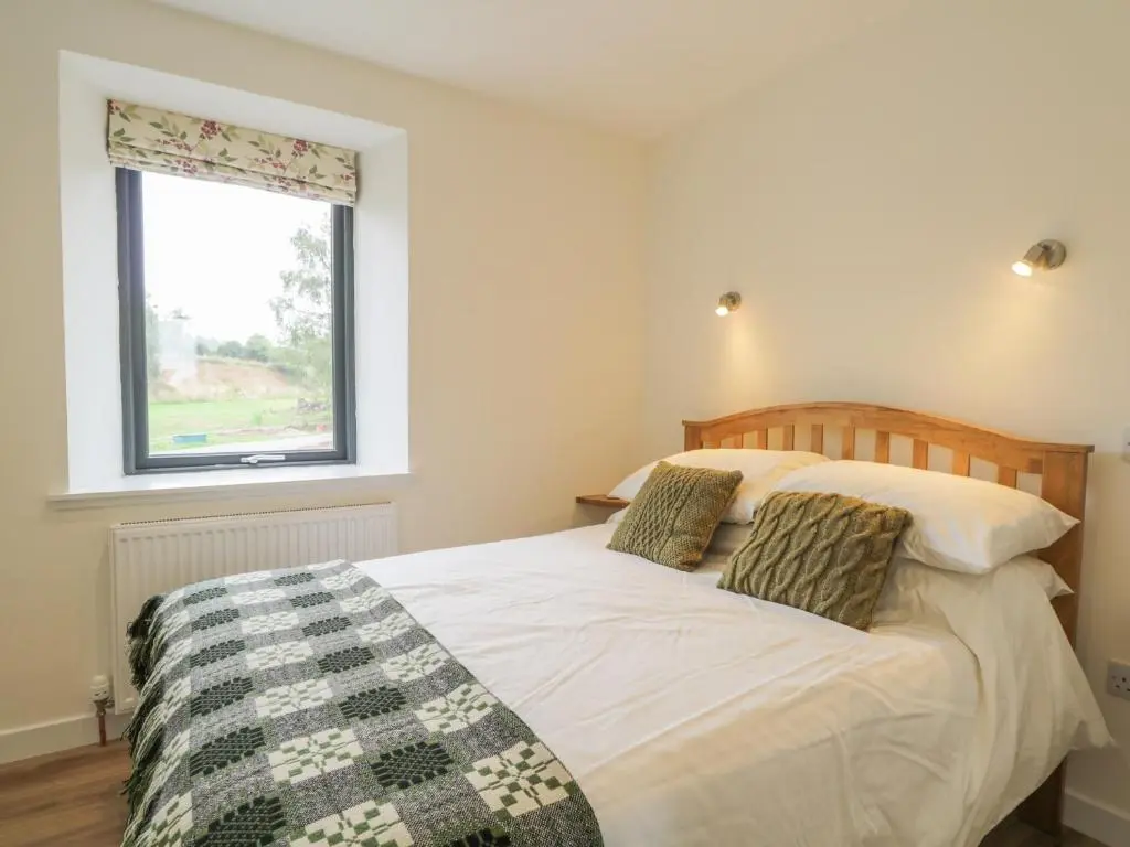 a bedroom with a large bed with a window at Enzie Station Cottage in Buckie
