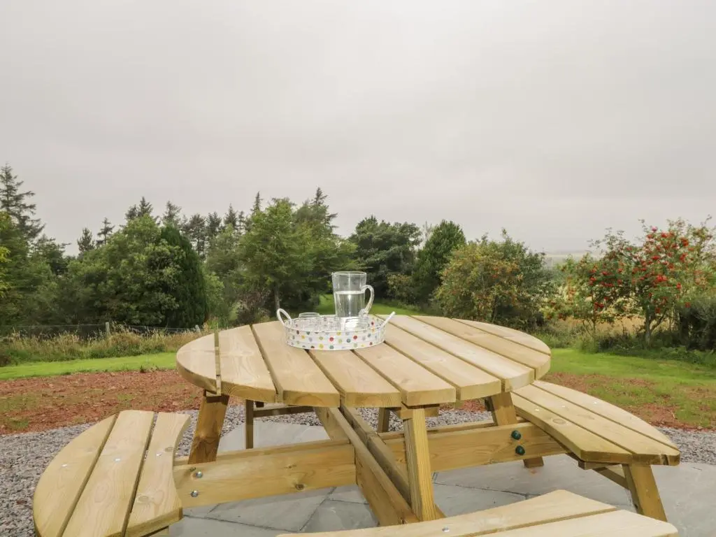a wooden picnic table with a wine glass on it at Enzie Station Cottage in Buckie