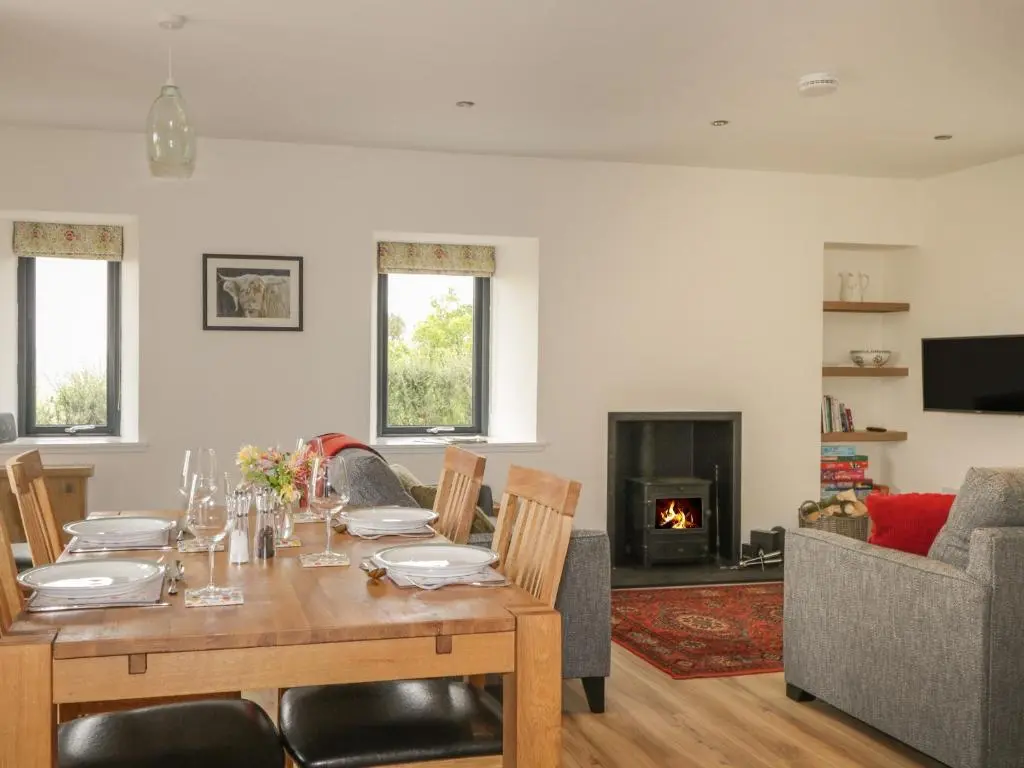 a dining room with a table and a couch at Enzie Station Cottage in Buckie