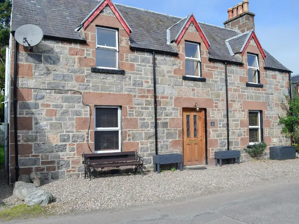 an old brick building with a wooden door and a bench at East Lewiston in Drumnadrochit