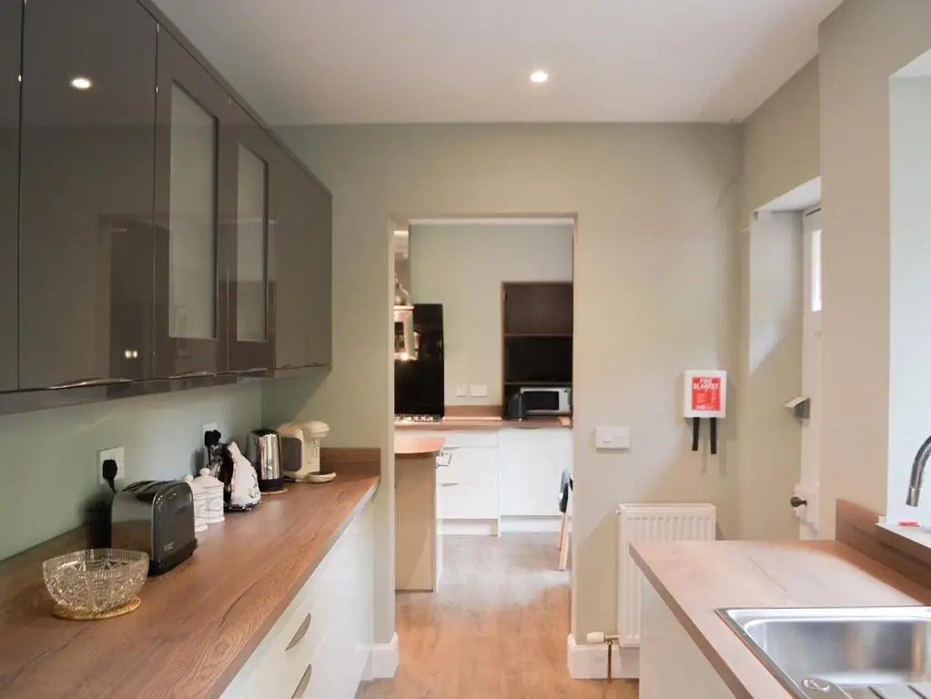 a kitchen with white cabinets and a wooden counter top at Braehead in Nairn