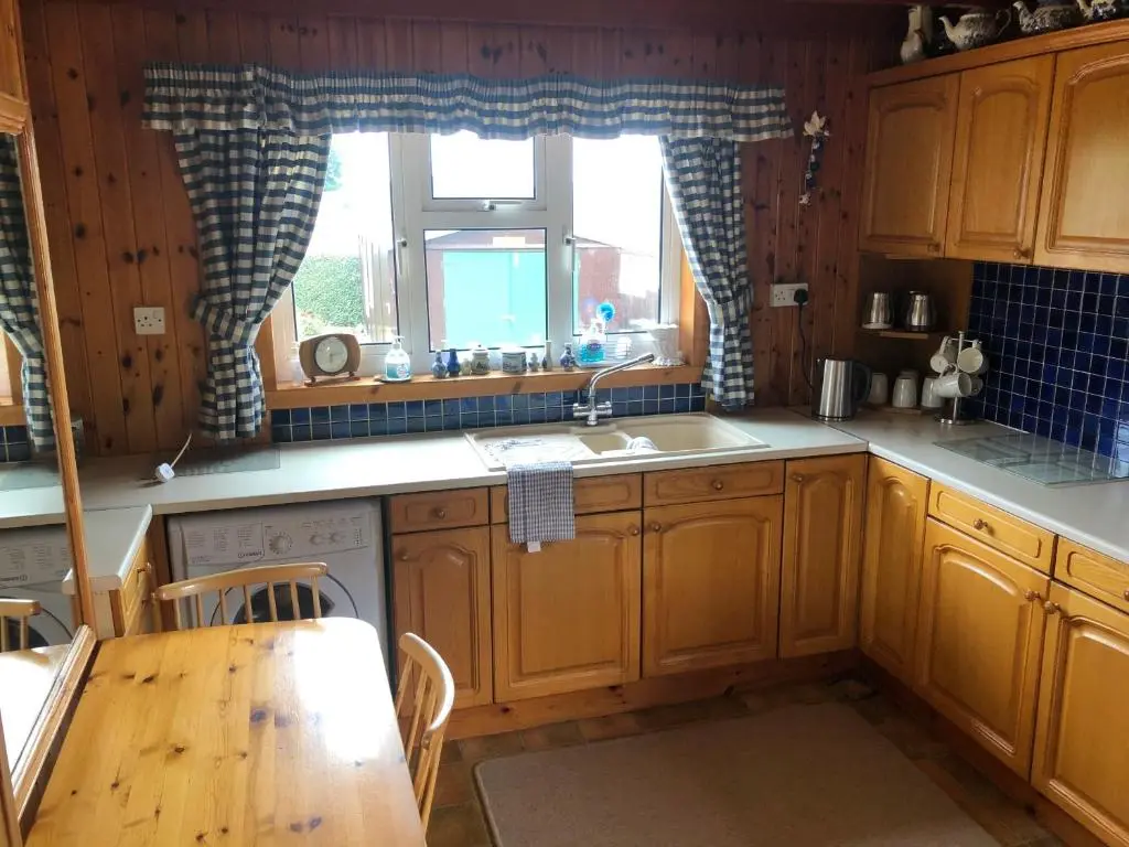 a kitchen with wooden cabinets and a table and a sink at Dallaire House in Banchory