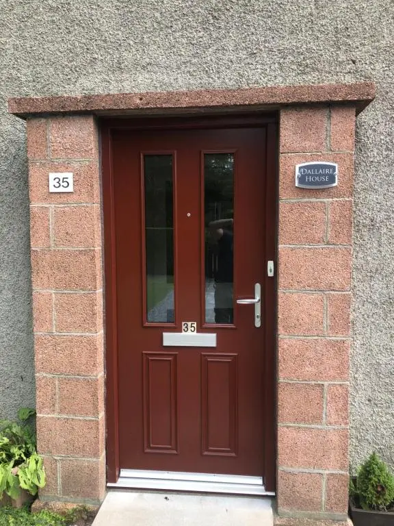 a red door in a brick building with a sign on it at Dallaire House in Banchory