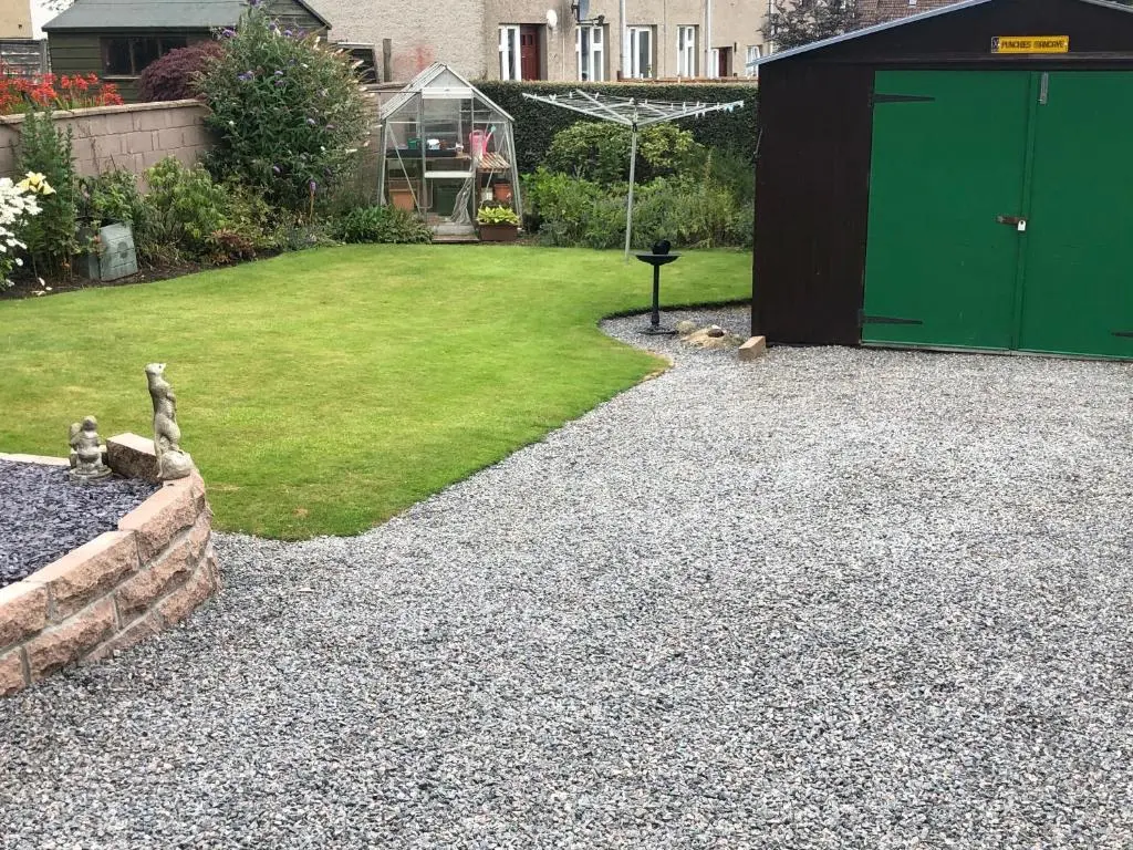 a gravel yard with a green door and a lawn at Dallaire House in Banchory