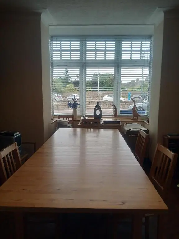 a large wooden table in a room with a large window at BELLEVILLE BED AND BREAKFAST in Elgin