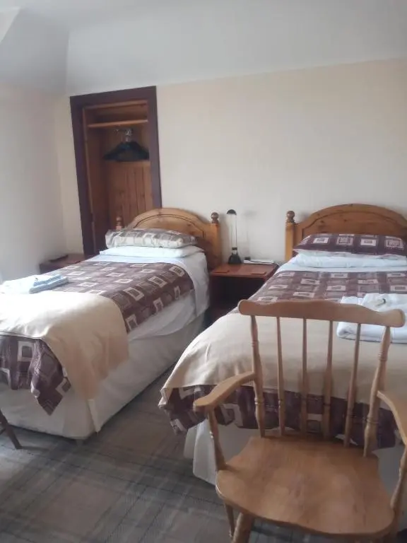 a bedroom with two beds and a chair in it at BELLEVILLE BED AND BREAKFAST in Elgin