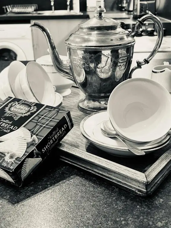 a tea pot and plates and a book on a kitchen counter at Dalmore in Nairn