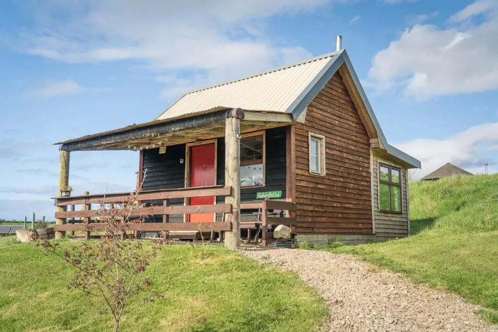a small wooden house on a hill with a green field at Shepherd's Loch Glamping in Turriff