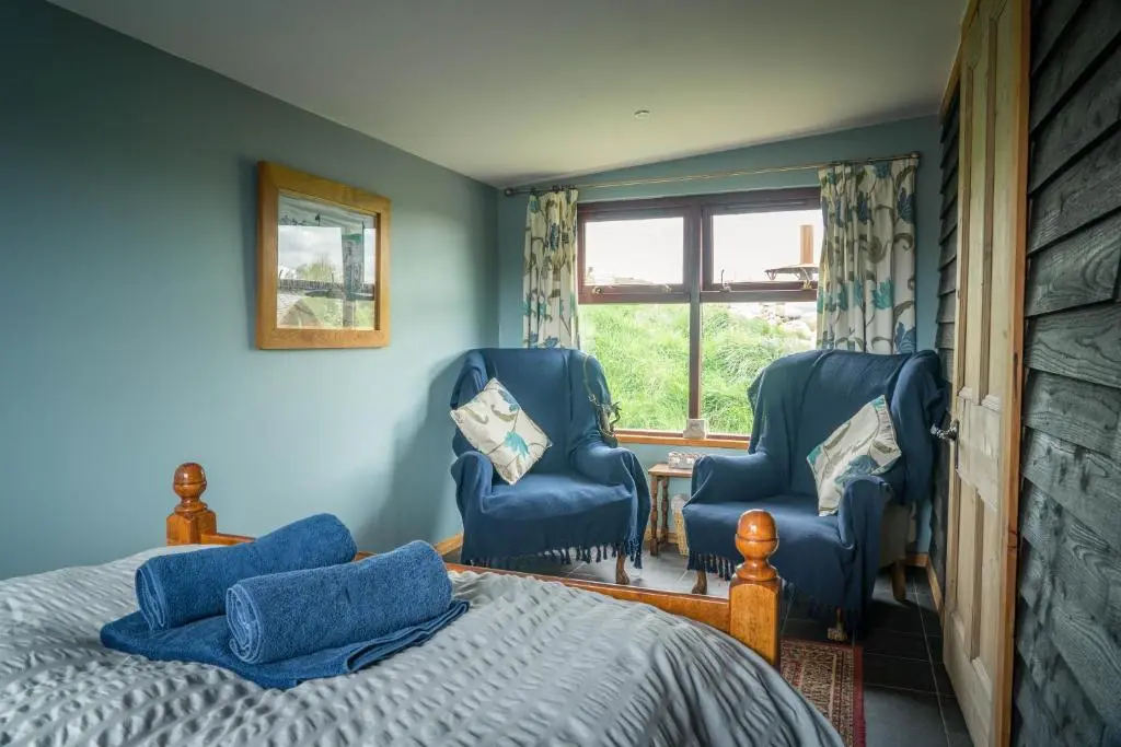 a bedroom with two chairs and a bed and a window at Shepherd's Loch Glamping in Turriff