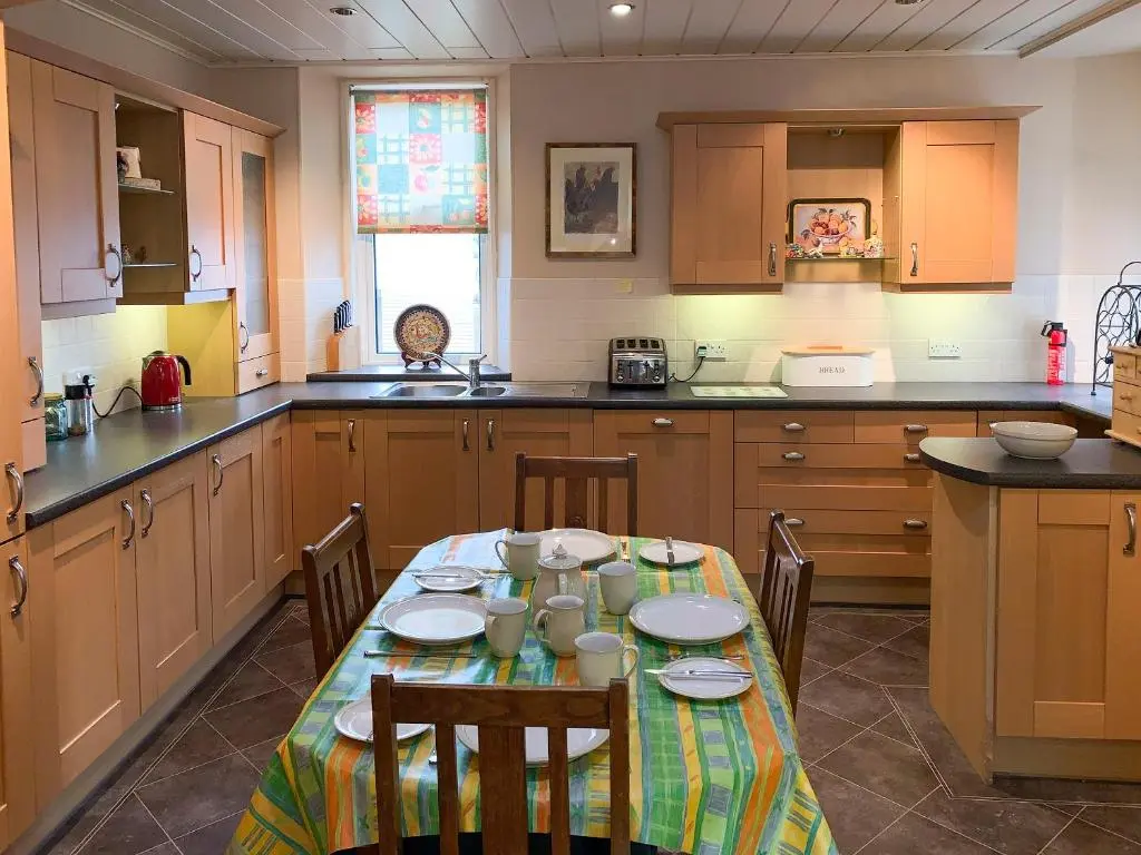 a kitchen with a table with chairs in it at The Coyles - Uk31466 in Ballater