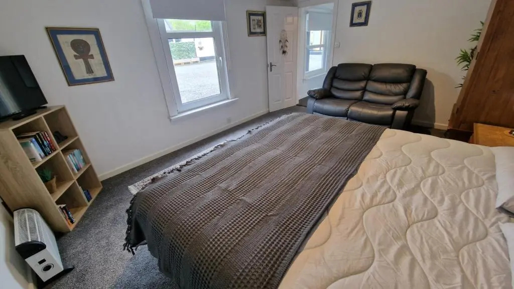a bedroom with a bed and a chair and a television at Spacious well equipped Chalet Bungalow close to Nairn, in Auldearn