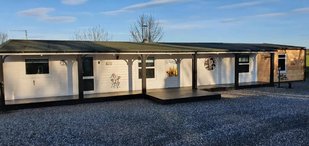 a white building with a roof on a gravel lot at Spacious well equipped Chalet Bungalow close to Nairn, in Auldearn