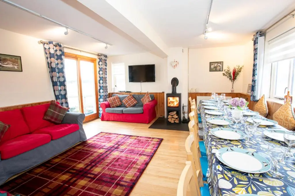 a living room with a long table with plates on it at Glenfeshie Hostel in Insh