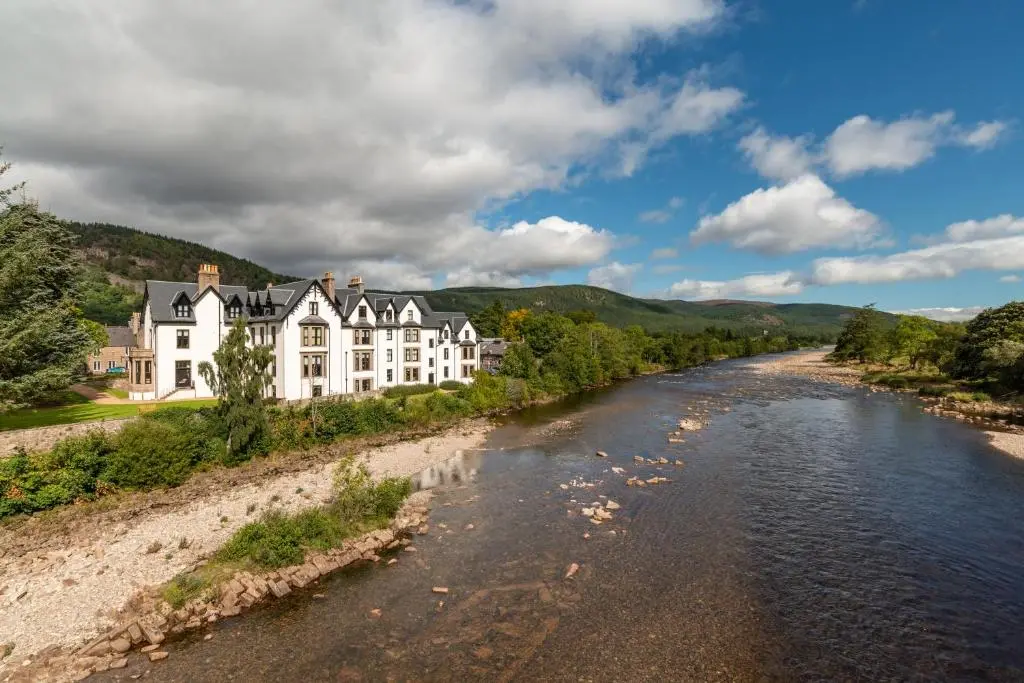a large white house on the side of a river at Historic Village, Rare Find, Amazing Views in Ballater
