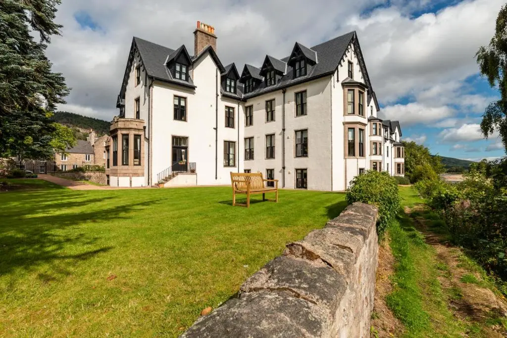 a large white house with a stone wall at Historic Village, Rare Find, Amazing Views in Ballater