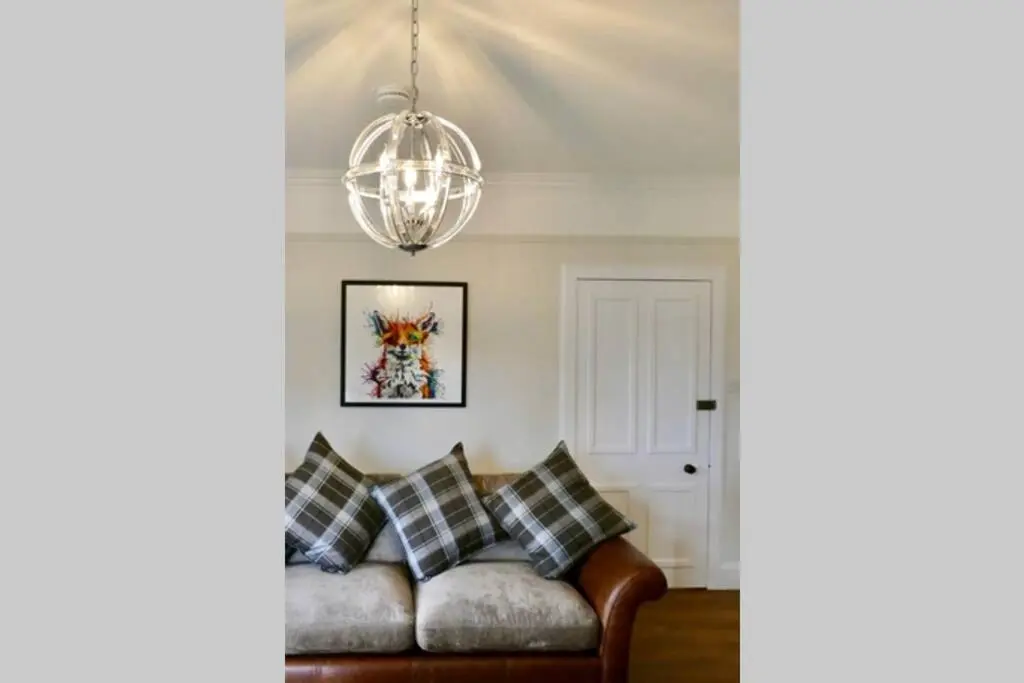 a living room with a couch and a chandelier at St Brendans Apartment in Elgin