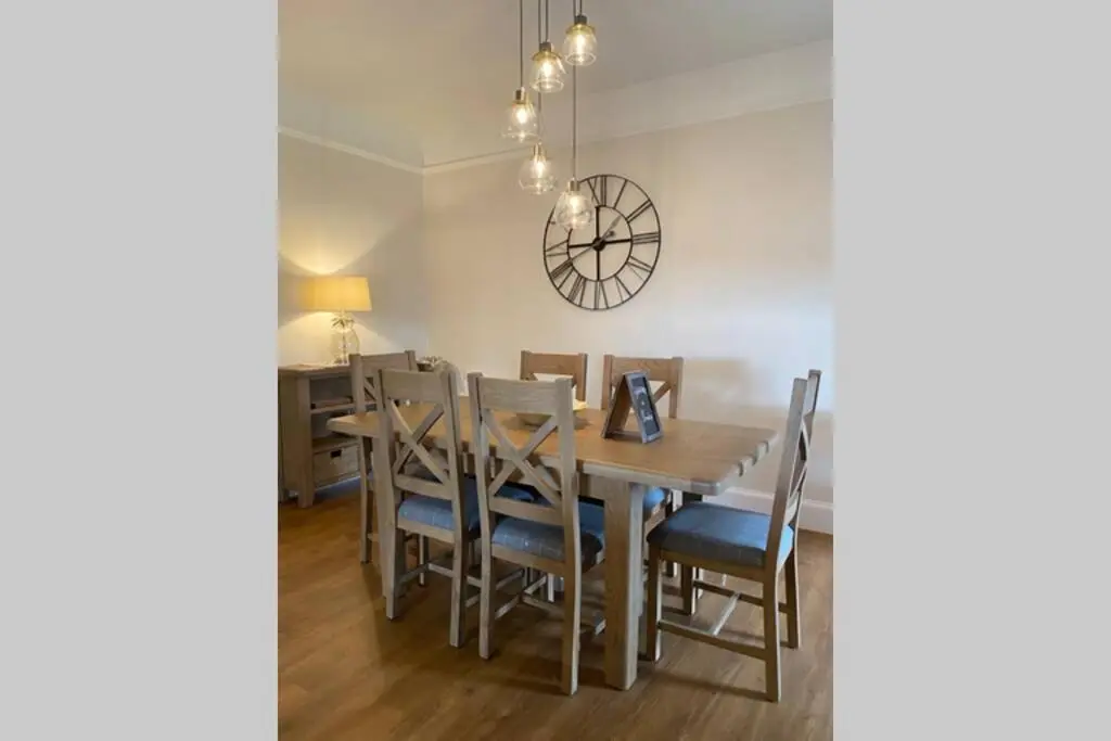 a dining room with a table and chairs and a clock at St Brendans Apartment in Elgin