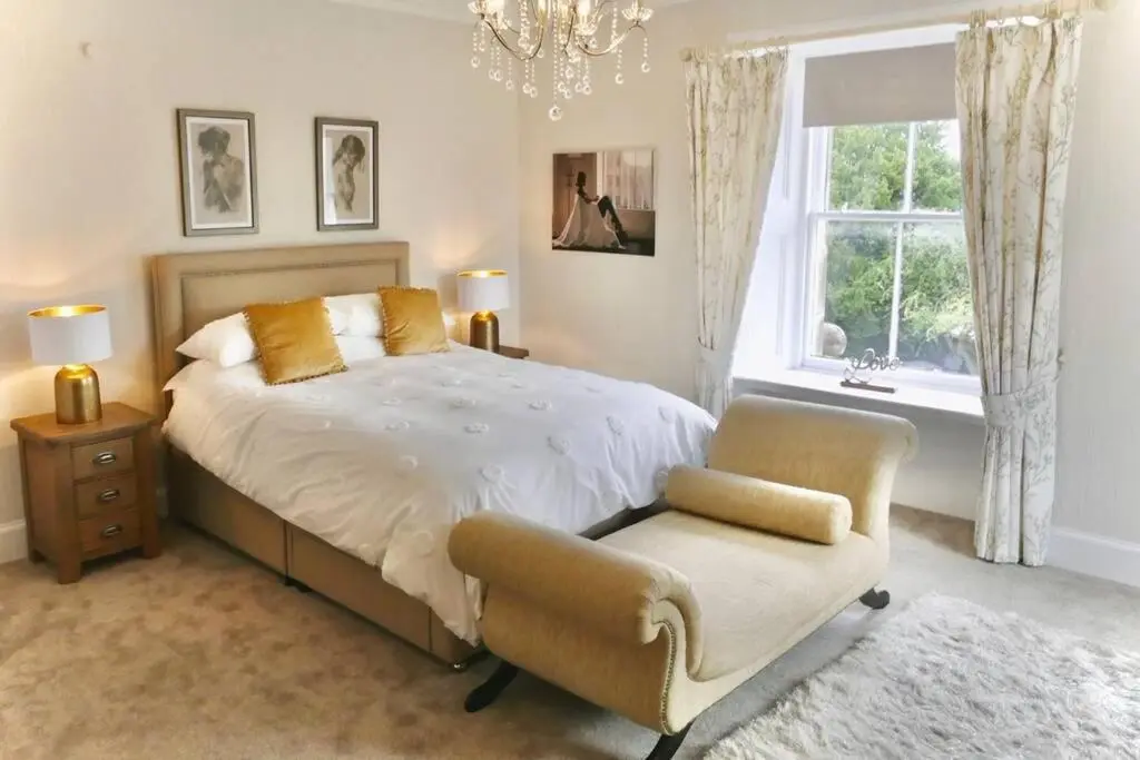 a bedroom with a bed and a chair and a window at St Brendans Apartment in Elgin