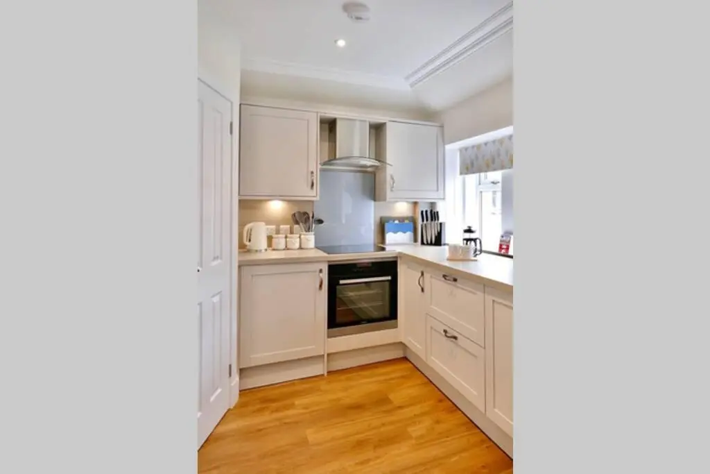 a kitchen with white cabinets and a wooden floor at St Brendans Apartment in Elgin