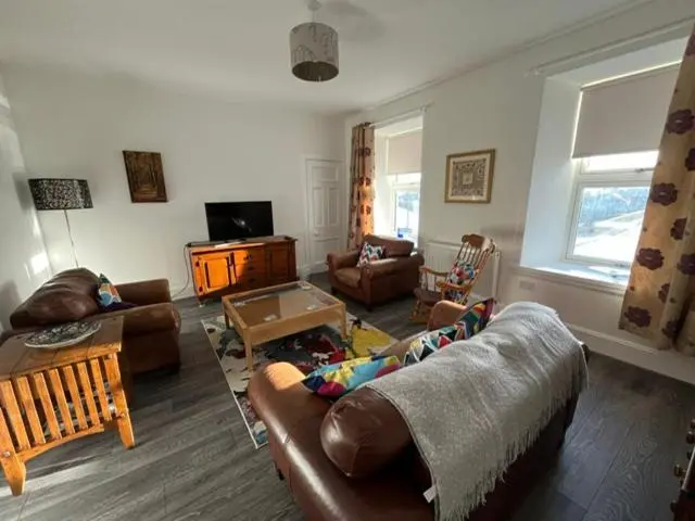 a living room with a couch and a table at Centrally located 2 bed modern flat with harbour views in Wick