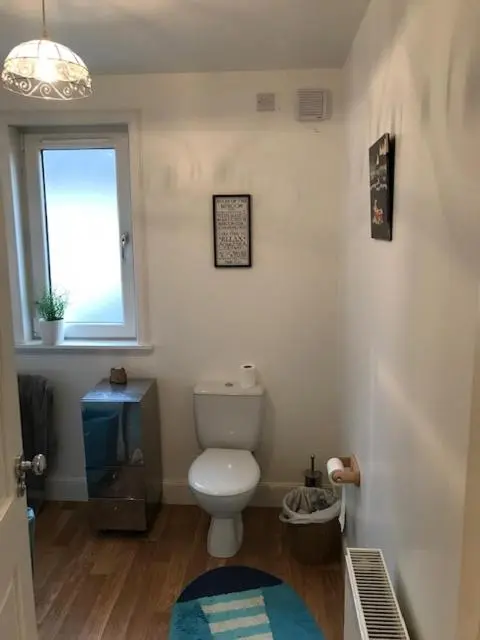 a bathroom with a toilet and a window at Centrally located 2 bed modern flat with harbour views in Wick