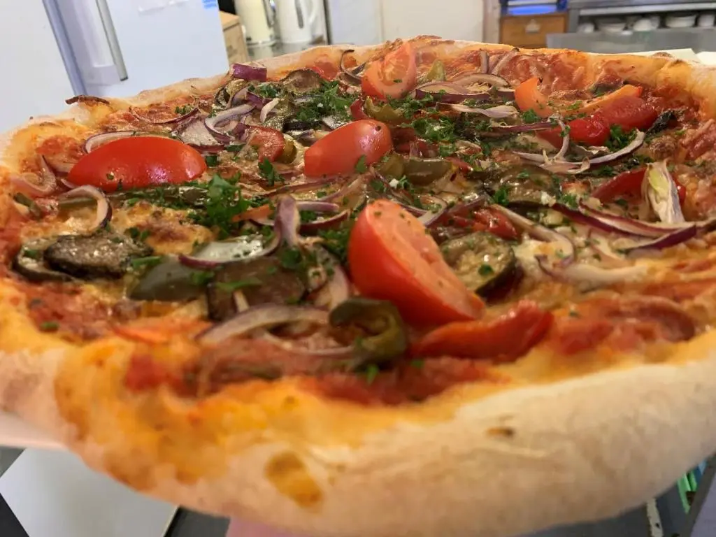 a pizza with tomatoes and onions on a table at The Aberdeen Arms Hotel in Tarves