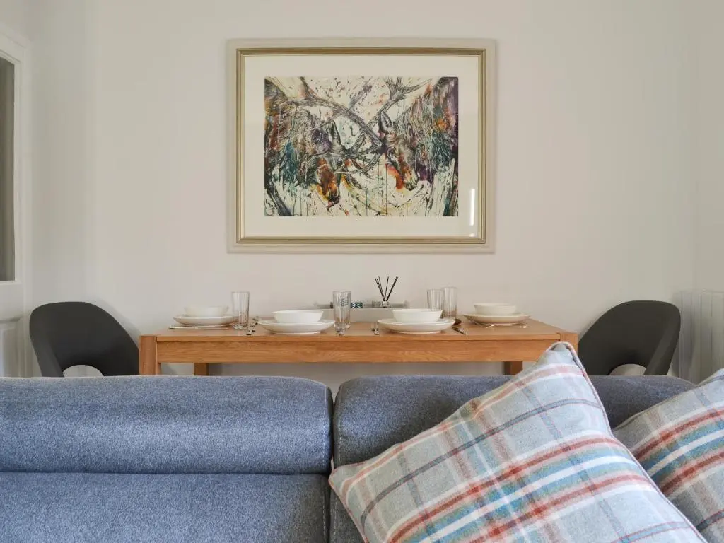 a living room with a couch and a table at Uaine Cottage in Aviemore