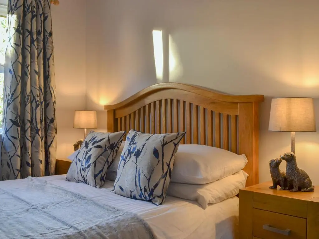 a bedroom with a bed with blue and white pillows at Uaine Cottage in Aviemore