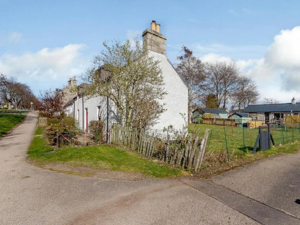 a white house with a fence next to a street at 19 South Street in Grantown on Spey