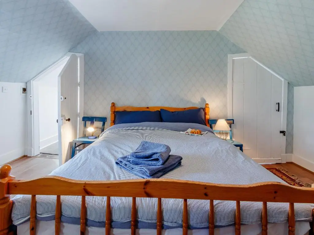 a bedroom with a wooden bed with a towel on it at 19 South Street in Grantown on Spey