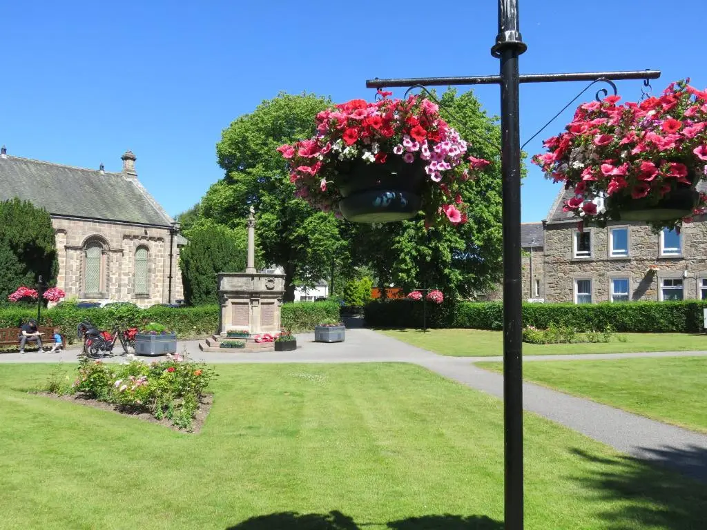 two hanging baskets of flowers on a pole in front of a building at Bankhouse B&B in Aberlour