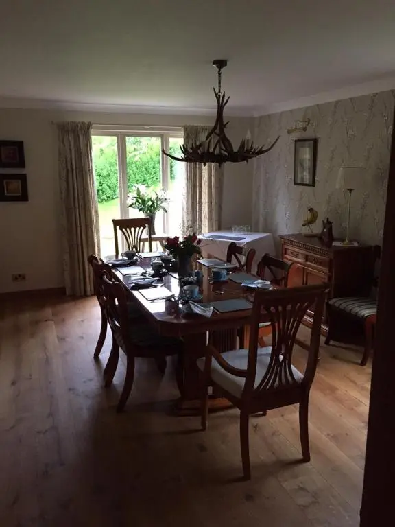 a dining room with a wooden table and chairs at Highfield House in Dornoch