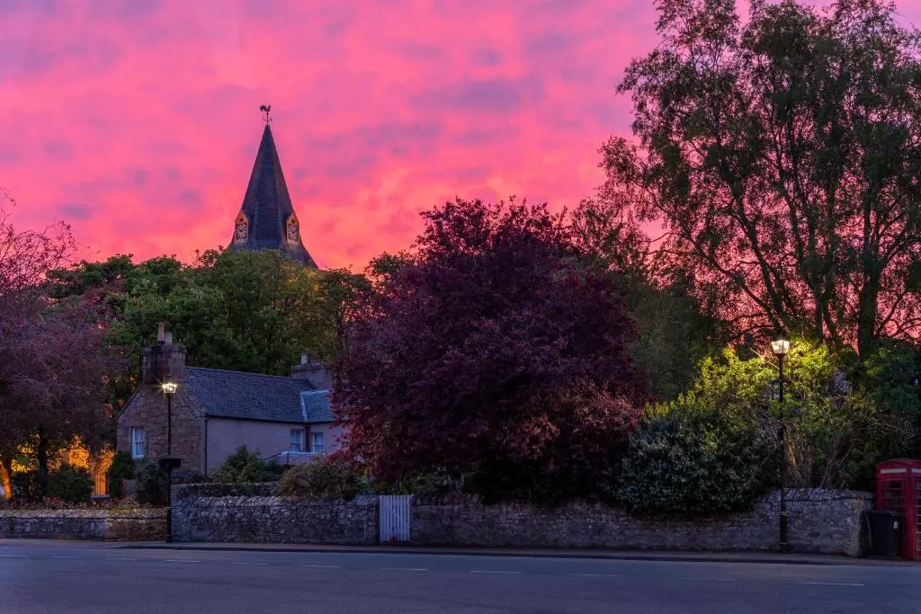 a sunset with a church and a red sky at Highfield House in Dornoch