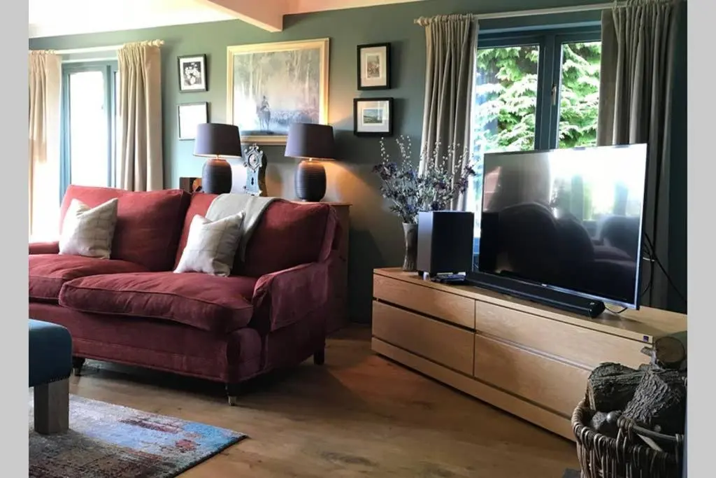 a living room with a red couch and a flat screen tv at Highfield House in Dornoch