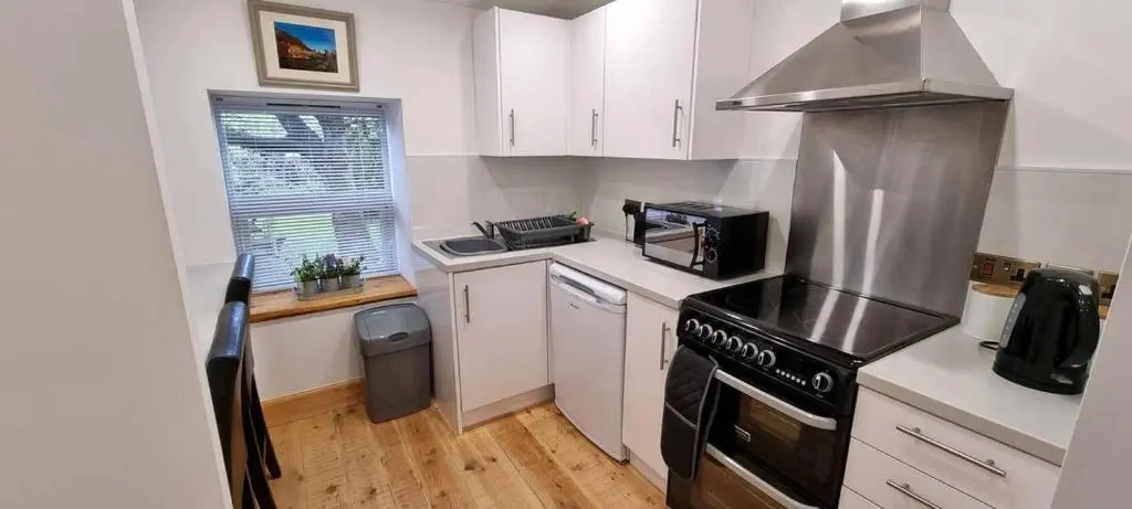 a kitchen with white cabinets and a stove top oven at The Coal Office Aberlour in Aberlour