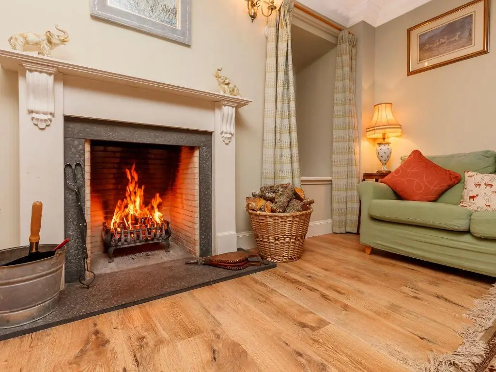 a living room with a fireplace and a green couch at Rowan House in Inveran