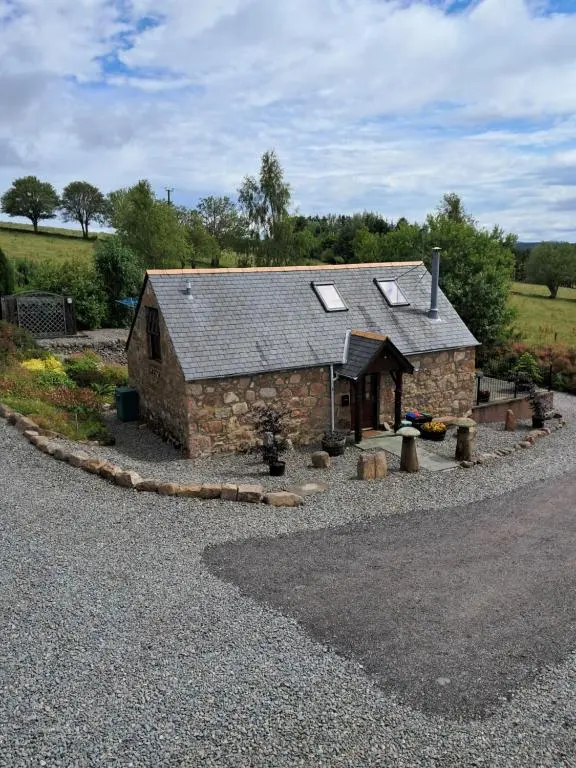 a small stone building with windows on a road at Boghead Cottage: Holiday Cottage in Royal Deeside in Banchory