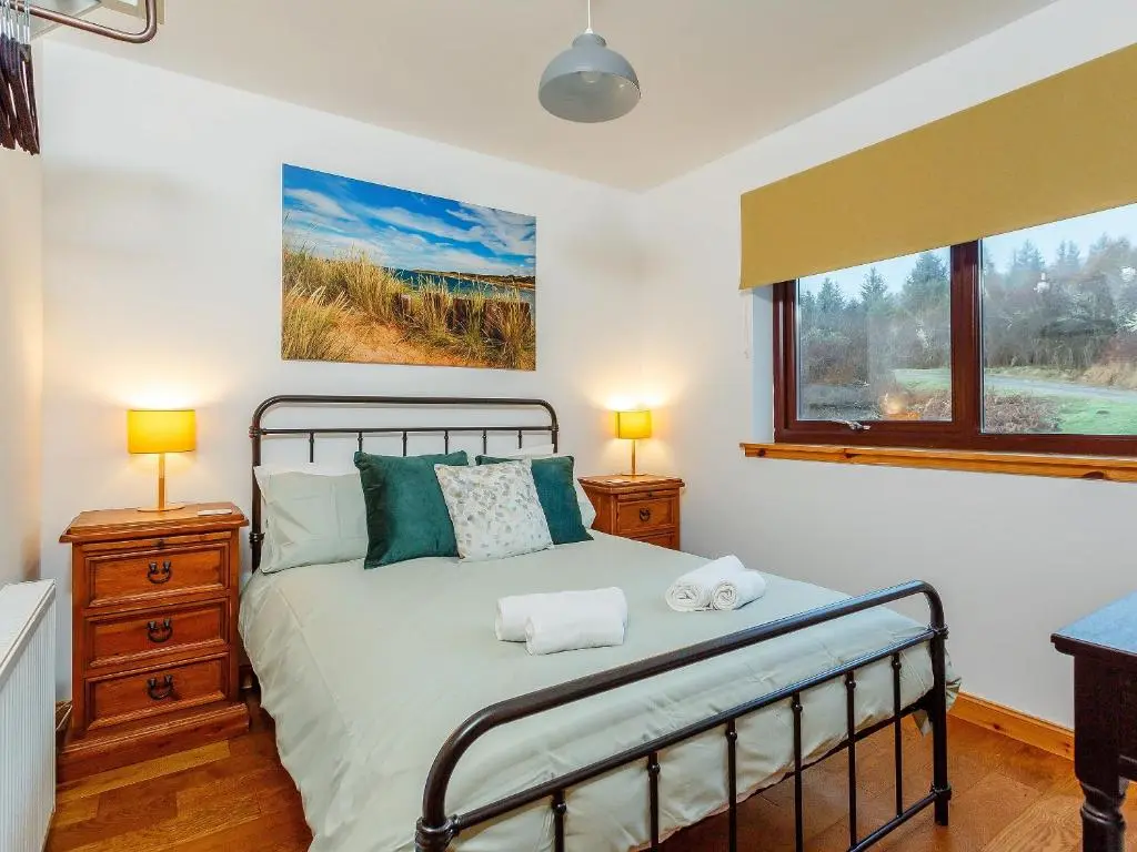 a bedroom with a bed with two lamps and a window at The Big Hoose in Achnahanat